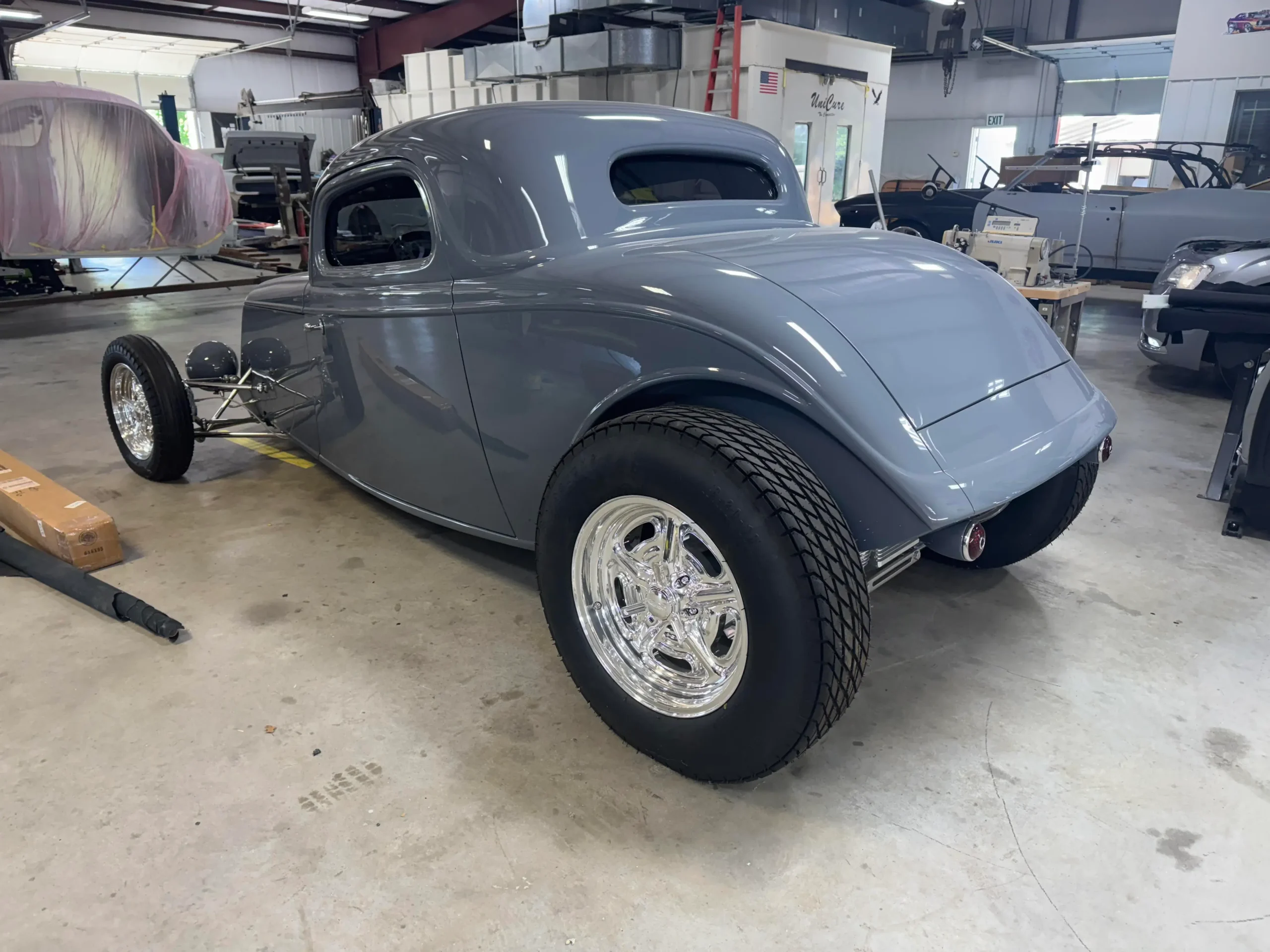 1933 Ford Coupe custom restoration with gray paint, polished wheels, wide rear tires, and classic hot rod styling
