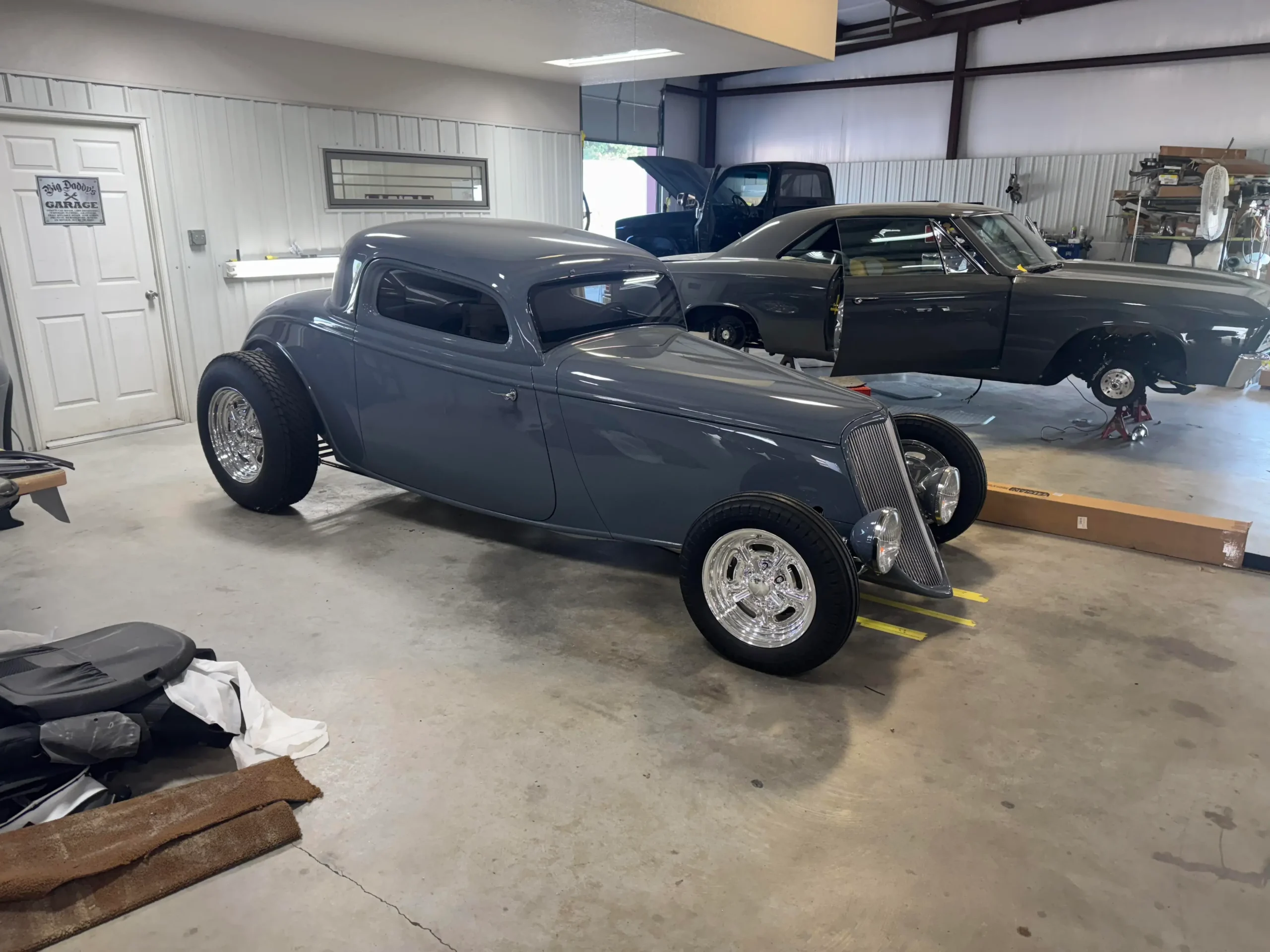 1933 Ford Coupe custom restoration with gray paint, polished wheels, wide rear tires, and classic hot rod styling