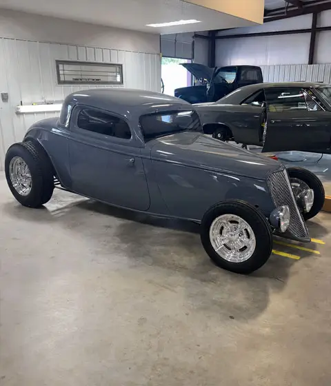 1933 Ford Coupe custom restoration with gray paint, polished wheels, wide rear tires, and classic hot rod styling