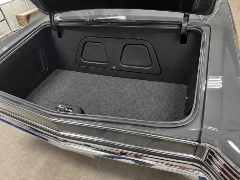 Finished custom trunk of a restored gray 1967 Chevrolet Chevelle with black panels and gray carpeting.