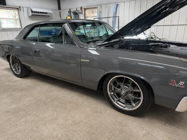 Passenger-side view of a completed gray 1967 Chevrolet Chevelle with its hood open inside the D & D Specialty Cars workshop.