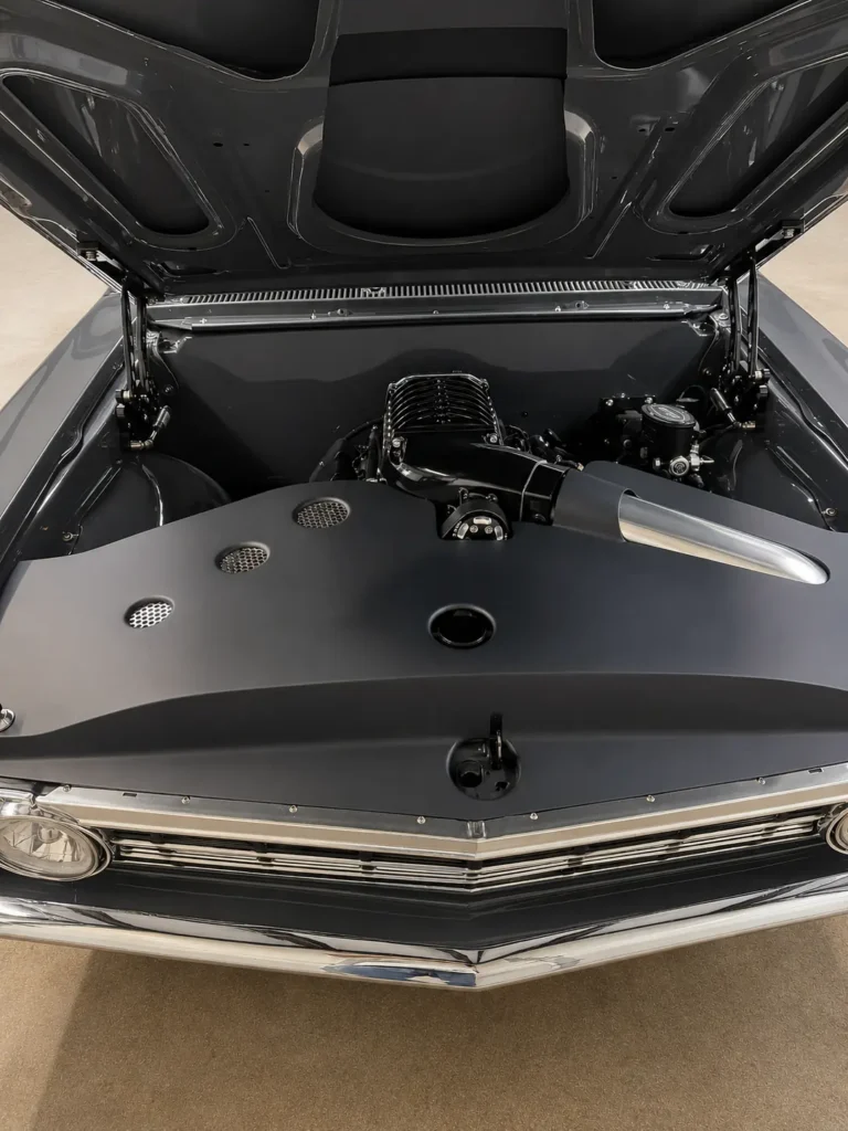 Custom supercharged engine bay of a completed gray 1967 Chevrolet Chevelle with matte-black closeout panels.
