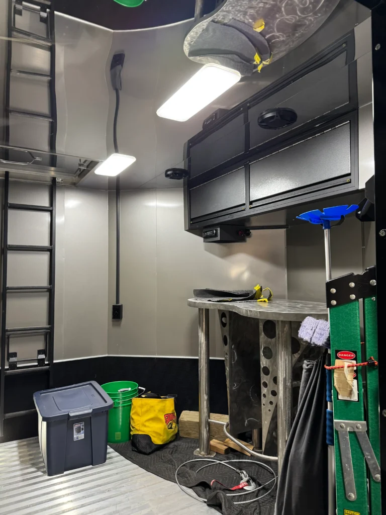 2019 Renegade Stacker Trailer interior with storage cabinets, work surface, ladder, and bright lighting